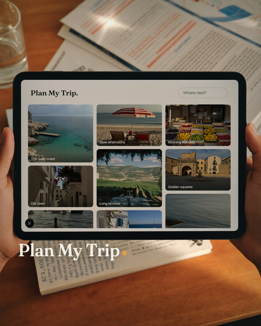 Plan My Trip brand film still: a travel designer's hand holding a phone over itinerary proofs at golden hour
